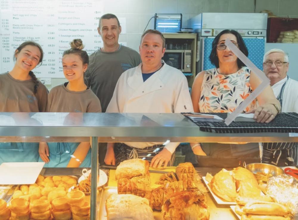 Corner Café team behind the counter, with scones, pasties and pies in the hot cabinet in front of them